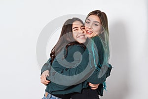 Two funny happy women girl friends embrace on white background. women`s friendship, sisters, youth