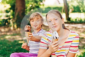 Two funny kids eating ice cream in summer park