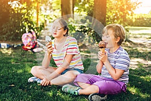 Two funny kids eating ice cream in summer park