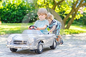 Two funny little friends playing with big old toy car