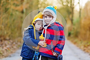 Two funny little kid sibling boys hugging on cold day