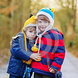 Two funny little kid sibling boys hugging on cold day