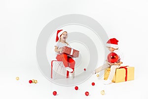 Two funny little kids in Santa hat sitting on gift boxes. Isolated on white background. Christmas and new year concept