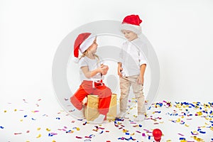 Two funny little kids in Santa hat sitting on gift boxes. Isolated on white background. Christmas and new year concept