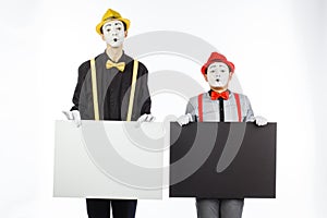Two funny mimes holding a white blank on a white background.