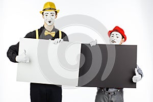 Two funny mimes holding a white blank on a white background.