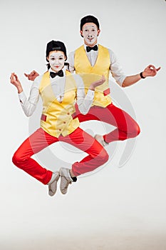 Two funny mimes jumping on white background