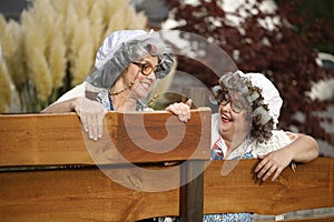 Two funny old Women looking over the garden fence