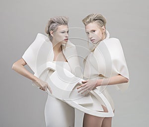 Two futuristic blonde women in white outfit