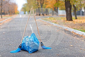 Two garbage bags with two brooms above them