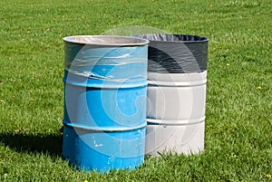 Two garbage bins on green grass.