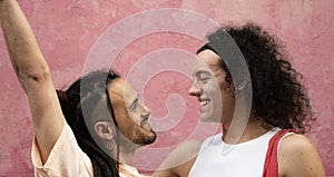 Two gay couple men are smiling and looking at each other with love and happiness  on pink background
