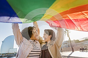 Two gay girls laughing with rainbow flag