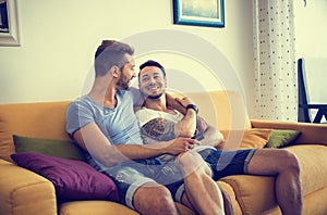 Two gay men on sofa embracing at home