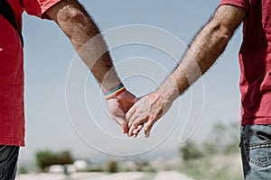 Two gay men shake hands with an LGBT bracelet.LGTB,LGBT