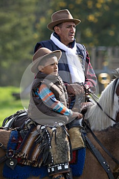 Two generations of cowboys in saddle