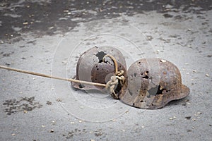 Two german military helmets perforated with bullets pull on a rope on asphalt as a symbol of great victory