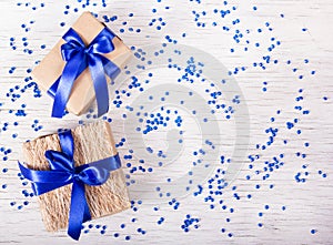 Two gift boxes with blue ribbons on a white background with sparkles. Copy space