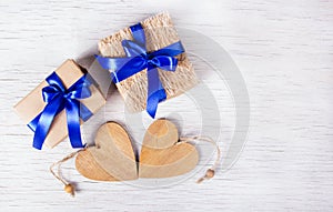 Two gift boxes with blue ribbons and wooden hearts on a white background. Valentine`s Day. Copy space.