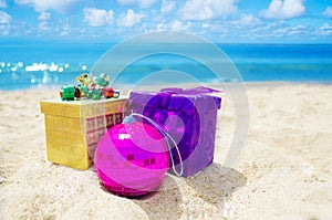 Two gift boxes with Christmas ball on the beach - holiday concept