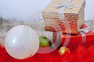 Two gift boxes and two Christmas balls on red and white fur.