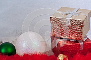 Two gift boxes and two Christmas balls on white and red fur with a white background.