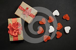 Two gift boxes and heart shaped candy on black