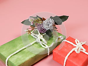 Two gift boxes with artificial flower decoration on pink background