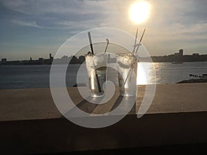 Two gin and tonics on rooftop at sunset