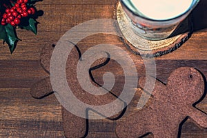 Two gingerbread man cookies with a glass of milk on a wooden backgroun, close up. Holiday concept, macro photography