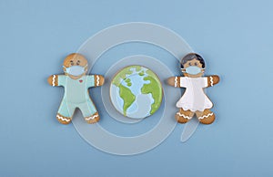 two gingerbread man medics in a mask girl and boy, gingerbread planet earth in the middle