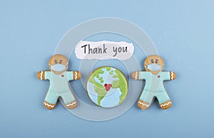 two gingerbread man medics in a mask, the inscription thank you and gingerbread planet earth in the middle