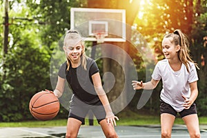 two girl child in sportswear playing basketball game