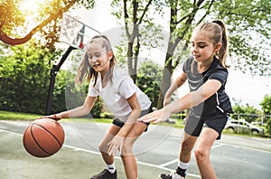 two girl child in sportswear playing basketball game