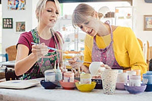 Two girl friends painting their own handmade ceramics