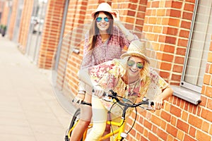 Two girl friends riding tandem bicycle