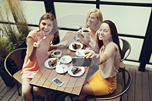 Two girl friends spend time together drinking coffee in the cafe, having breakfast and dessert.