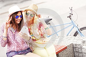 Two girl friends using smartphone while riding tandem bicycle