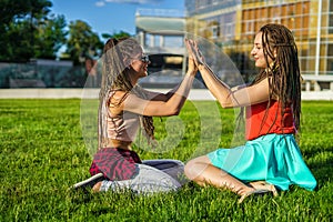 Two girl friends with zizi cornrows dreadlocks giving high five to each other