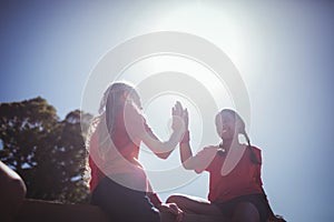 Two girl giving high five to each other during obstacle course training