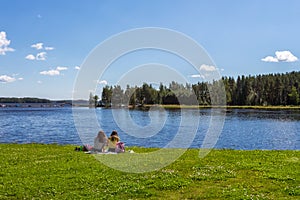 Two girl are resting on lake shore