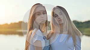 Two girlfriends blondes posing in front of the camera at sunset.