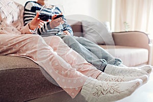 Two girlfriends drinking wine sitting on couch at home. Women talking and relaxing