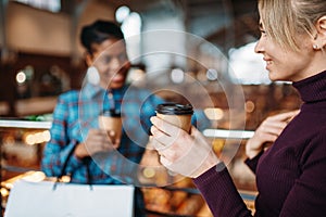 Two girlfriends drinks coffee after shopping