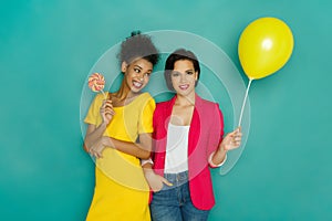 Two girlfriends having fun at turquoise studio background