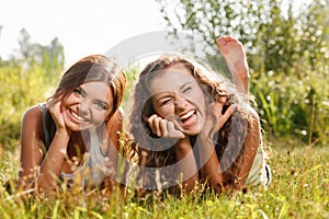 Two girlfriends lying down on grass