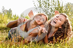 Two girlfriends lying down on grass