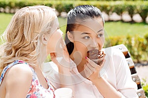 Two girlfriends in park with coffee and cupcakes