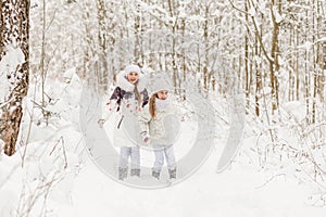 Two girlfriends playing in a winter forest.