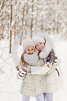 Two girlfriends playing in a winter forest.